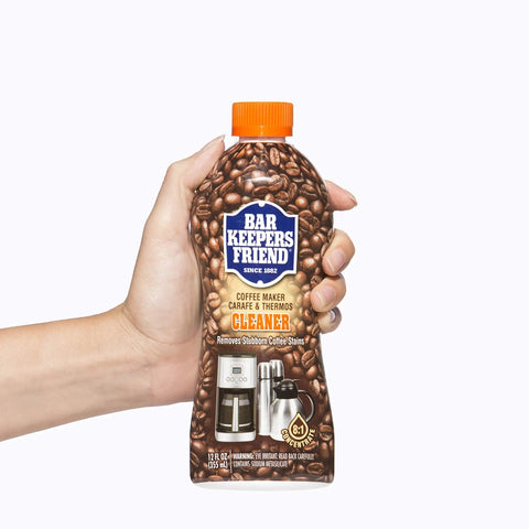 Hand holding a 12 oz bottle of Coffee Maker Cleaner That Kicks Oily Residue, Tannins, And Stains For Single Cup And Auto Drip Machines