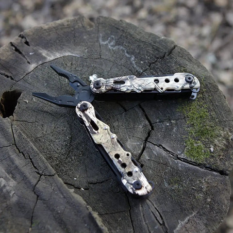13 In 1 Outdoor Folding Multitool Pliers In Camo With Knife Saw Pliers Wire Cutter Screwdrivers Leather Punch Bottle Opener And Can Opener For Camping Fishing Hiking Survival on tree stump