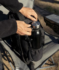 Person placing a bottle in Wakizashi Tactical Backpack 24L With MOLLE System Durable 100 Percent Polyester Gear Pack For EDC Outdoor And Tactical Use 17.1 By 11.1 By 6.1 Inches Black on a chair
