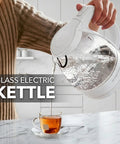 1.5 Liter Glass Electric Kettle With Blue Led Glow pouring hot water into a glass cup on a marble countertop.