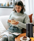 Woman enjoying coffee with 4 In 1 Electric Milk Frother And Steamer For Hot And Cold Foam 11 Oz Capacity Makes Latte Cappuccino And Hot Chocolate