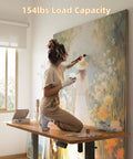 Artist using Electric Standing Desk 48 By 24 Inches With Adjustable Height as a workstation for painting, showcasing 154 lb load capacity