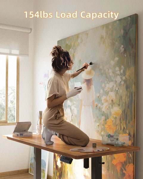 Artist using Electric Standing Desk 48 By 24 Inches With Adjustable Height as a workstation for painting, showcasing 154 lb load capacity