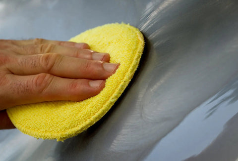 Hand using Microfiber Polishing Pads Set For Car Detailing 5 Inch Yellow 6 Pack Ultra Soft Cleaning Pads