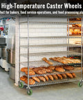 Four-tier chrome bakery rack on green caster wheels loaded with loaves of bread