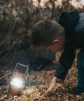 Child examining ground lit by 4 Pack Multicolor Camping Lanterns, Ultra Bright LED Tent Lights for Power Outages, battery powered.