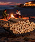 Sturdy Steel Firewood Rack For Indoor And Outdoor Use 32 Inch Log Holder with logs on a beach at sunset, people near a fire