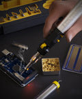 Hand using Butane Soldering Iron Multi Purpose Kit Cordless Self Igniting Adjustable Flame 7 Tip Set Pro Grade 125 Watt Equivalent 13 Piece Accessory Bundle For Electronics Jewelry Plumbing And More on circuit board