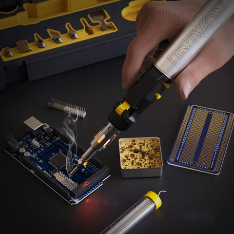 Hand using Butane Soldering Iron Multi Purpose Kit Cordless Self Igniting Adjustable Flame 7 Tip Set Pro Grade 125 Watt Equivalent 13 Piece Accessory Bundle For Electronics Jewelry Plumbing And More on circuit board
