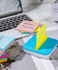 Burst Of Color Sticky Notes Refills 3x3 Pop Up Pads With 9 Bright Colors shown in dispenser on desk next to laptop