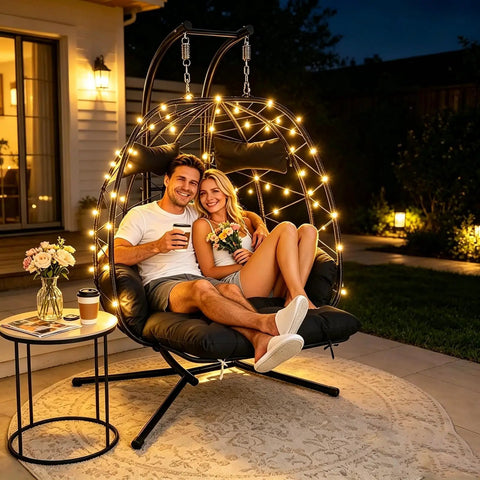Two Person Outdoor Hanging Egg Chair With Stand And Adjustable Footrest Oversized Wicker Swing Chair With Thick Cushions For Indoor And Outdoor Chill Cozy Relaxing Black With Footrest And Light, showing two people sitting, illuminated at night.