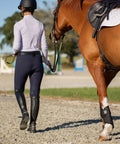 Rider leading horse in padded dressage bridle with reins and removable flash in black for warmbloods all day comfort on gravel path