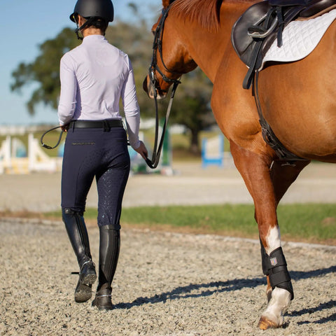 Rider leading horse in padded dressage bridle with reins and removable flash in black for warmbloods all day comfort on gravel path