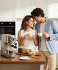 Pro Grade Espresso Machine With Milk Frother And Cappuccino Maker For Home Baristas Adjustable Temperature And Cup Size Built In Display Pressure Gauge Stainless Steel Body on a kitchen counter with a couple enjoying coffee