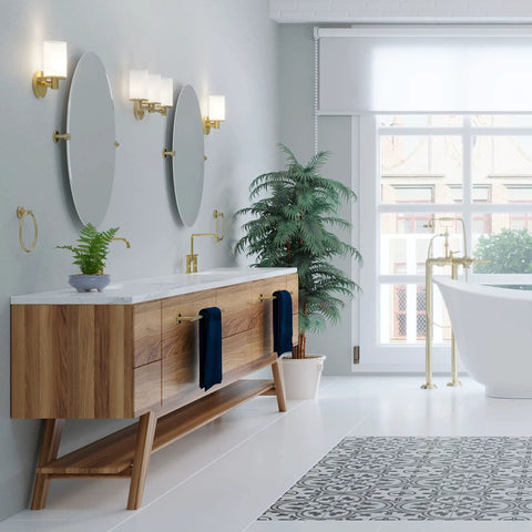 Modern bathroom with Latitude II 24 Inch Wall Mounted Towel Bar In Brushed Brass, wooden vanity, round mirrors, and green plant.