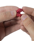 Hands holding GSP-24 24 Piece Twist-Apart Switch And Receptacle Spacers, showing red pro grade electrical spacers in detail