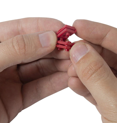 Hands holding GSP-24 24 Piece Twist-Apart Switch And Receptacle Spacers, showing red pro grade electrical spacers in detail