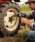 Person using tool on tractor wheel in field