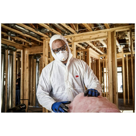 Person wearing All In One N95 Respirator For Sanding Drywall Painting And Woodworking With Exhalation Valve Directing Air Downward 10 Pack For Dust Fiberglass Particles And Non Oil Based Aerosols, handling insulation in construction site