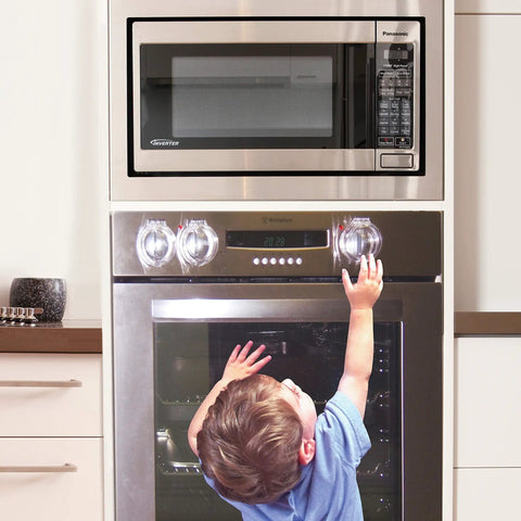 Child reaching for stove with Stove And Oven Knob Safety Cover Set L730A Five Count Pack Easy To Install Kid Safe Kitchen Accessory Clear