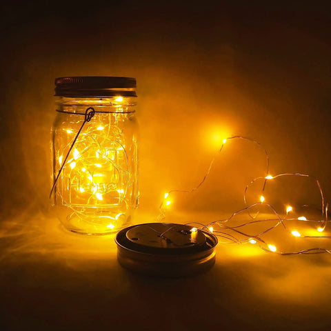 Lit Solar Mason Jar Lights 4 Pack With 30 LEDs Starry Fairy String Hanging Jar Lights glowing in dim light with jar and lid visible
