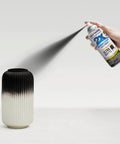 Rust-Oleum Painter's Touch 2X Ultra Cover spray paint can spraying matte black on a ribbed ceramic vase front view