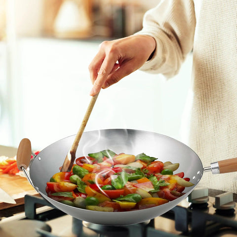 Cooking vegetables in Go-To 14-Inch Carbon Steel Wok With Bamboo Handle For Stir Frying, Sauteing, Steaming, Braising And Deep Frying.