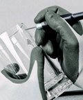 Close-up of hands with gloves using a tool to engrave a glass, showcasing detail and precision work.