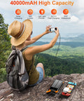 Person using Beast Solar Power Bank 40000mAh Portable Charger With PD 20W Fast Charging Built In 4 cables connected to devices outdoors