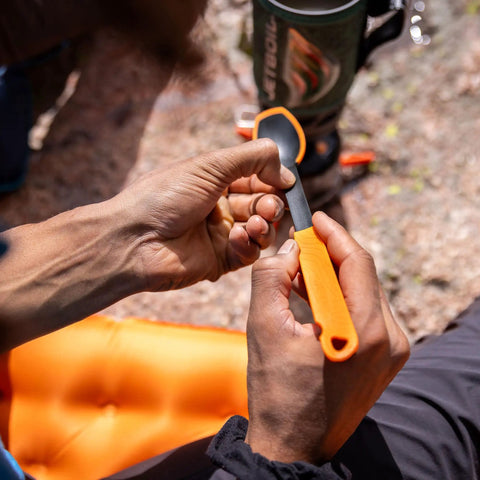 Hands holding TrailSpoon Extendable Backpacking Spoon With Silicone Edge For Pots Reach Inside Cookware During Camping Trips