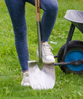 Round Point Gardening Shovel With Wood D Handle 41 Inch Steel Digging Spade For Lawn Yard Landscaping Heavy Duty Durable All Purpose Tool For Gardeners And Outdoor Projects in use on grass near a wheelbarrow.