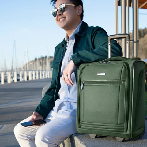 Man seated outdoors with Underseat Carry-On Luggage With 28L Capacity, Sustainable Travel Bag Made From Recycled RPET in Juniper Green next to him