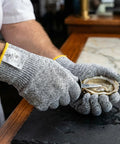 Person wearing Level 5 Cut Resistant Kitchen Gloves With HPPE opening oyster, showcasing food-grade material and protection.