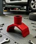 Beefy Bottle Jack Adapter Lifting Saddle For 2 To 4 Inch Axle Tubes in a garage setting with surrounding tools.