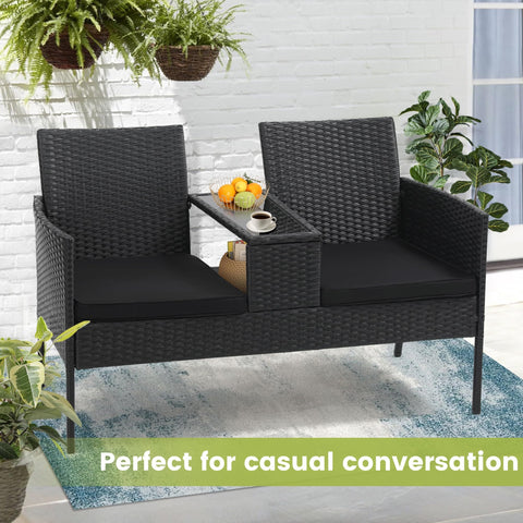 Two Seat Outdoor Patio Loveseat With Table In Black Wicker Rattan Outdoor Set With Washable Cushion Covers Weatherproof Garden Lounge Furniture For Backyard Lawn And Porch, displayed on a patio with plants.
