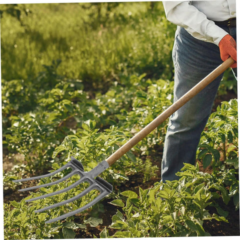 Heavy Duty Steel Garden Fork For Soil Loosening And Deep Soil Turning used in a garden by person wearing gloves and jeans