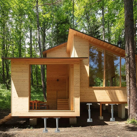 No Fuss 4 Pack Adjustable House Jacks Expanding 11.8 To 16 Inches With 8800 Lbs Per Unit supporting a wooden house in a forest.