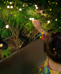 Child admiring Solar Firefly Lights for Outdoor Decor 6 Pack Real Firefly Look Waterproof Swaying Garden Lights in a planter
