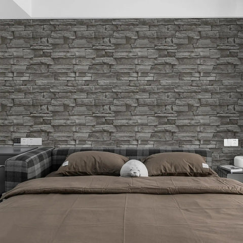 Bedroom with grey stone wall backdrop, twin beds with grey bedding, and decorative pillows, featuring stone texture.