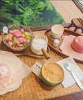 Table with pink teapot, dessert, colorful fruit bowl, and Double Scale Glass Measuring Cup with Wooden Handle for Coffee