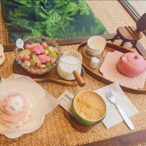 Table with pink teapot, dessert, colorful fruit bowl, and Double Scale Glass Measuring Cup with Wooden Handle for Coffee