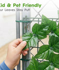 Close-up of a hand touching Ultra Realistic Artificial Ivy Privacy Fence Screen 120 By 40 Inches UV Resistant Faux Greenery
