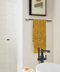 Slick Polished Nickel And Black Bronze Towel Bar, 24 Inch Towel Rack With Knurled Texture holding yellow towel in modern bathroom.