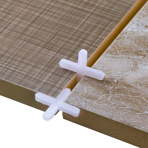 White plastic cross tile spacers between ceramic tile edges; 1/16 inch; close-up view.