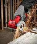 Milwaukee 12V cut-off tool, bare tool, side view cutting metal bar with sparks; red body, gray guard.