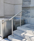 Hella Sturdy 3 Step Outdoor Handrail With Zero Sweat Diy Install Pack And Rugged 304 Stainless Steel Build For Porch Stairs On Concrete Brick Or Wood Planks Silver Finish Smooth Ride installed on concrete stairs next to a metal cart.