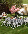 Outdoor setup with a Waterproof Vinyl Rectangle Table Cloth With Soft Flannel Backing, Spillproof And Wipeable Buffalo Check Black And White Table Cover For Dining, Kitchen, And Outdoor Use, 60 By 84 Inches on a table surrounded by chairs.