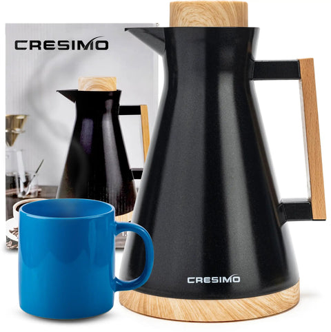 Vacuum Insulated Thermal Carafe 34 Oz Keeps Coffee Hot for 12 Hours with glass wall and beech wood accents next to a blue mug