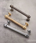 Three straight bar cabinet handles in polished chrome, brushed gold, and matte black finishes displayed on a marble surface.