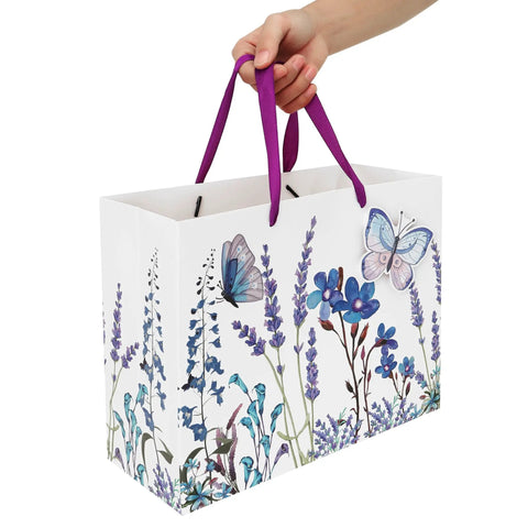13 Inch Large Purple Gift Bag Set With Lavender Theme 3D Butterfly Accents Greeting Card And Tissue Paper Perfect For Birthday Mothers Day Weddings Valentines Day Or Any Special Occasion displaying purple handles and hand holding.